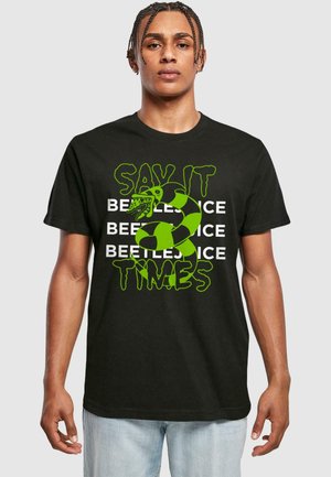 Sort bomulds T-shirt med fed grøn tekst, et slangediagram og et gentaget "BEETLEJUICE" mønster. Rund hals, korte ærmer, afslappet pasform.