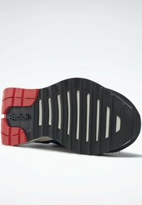 Svart gummisko sula med röda och grå accenter. Har ett randigt mönster och Reebok-logotypen präglad på den laterala sidan.