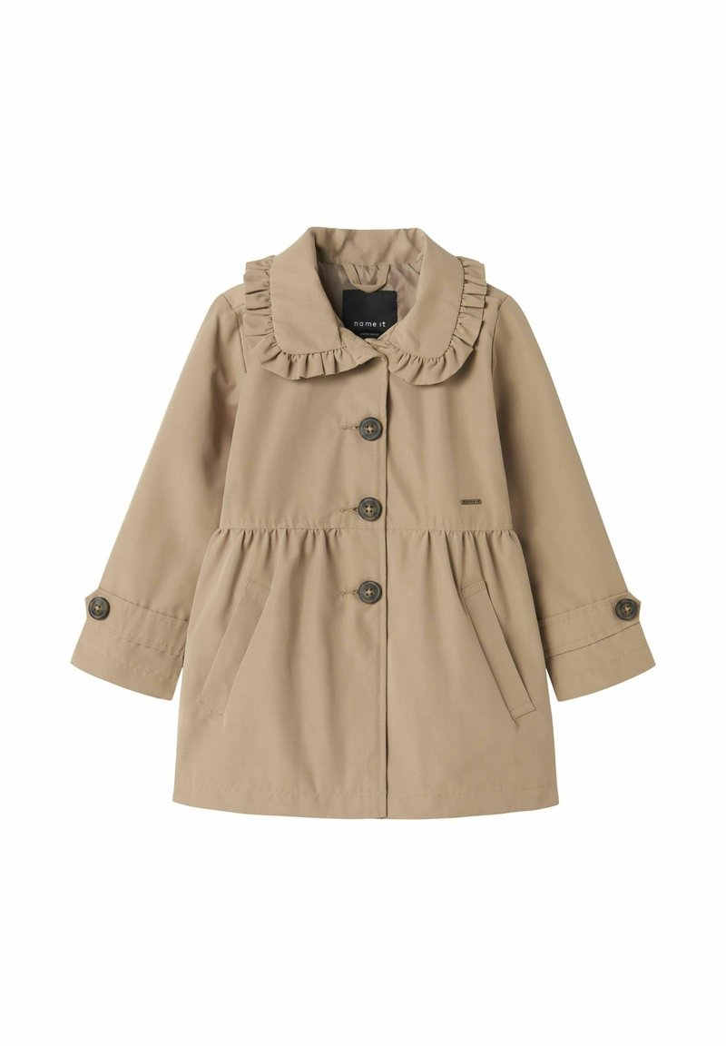 Manteau beige pour enfant avec col à volants, trois boutons sur le devant, poches latérales et poignets boutonnés.