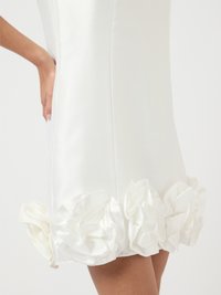 Λευκό φόρεμα με εφαρμοστό κορμό και φαρδύ τελείωμα διακοσμημένο με στρώσεις σατέν βολάν. Λείο υλικό, μήκος μέχρι το γόνατο και χωρίς ορατές κλείστρα.