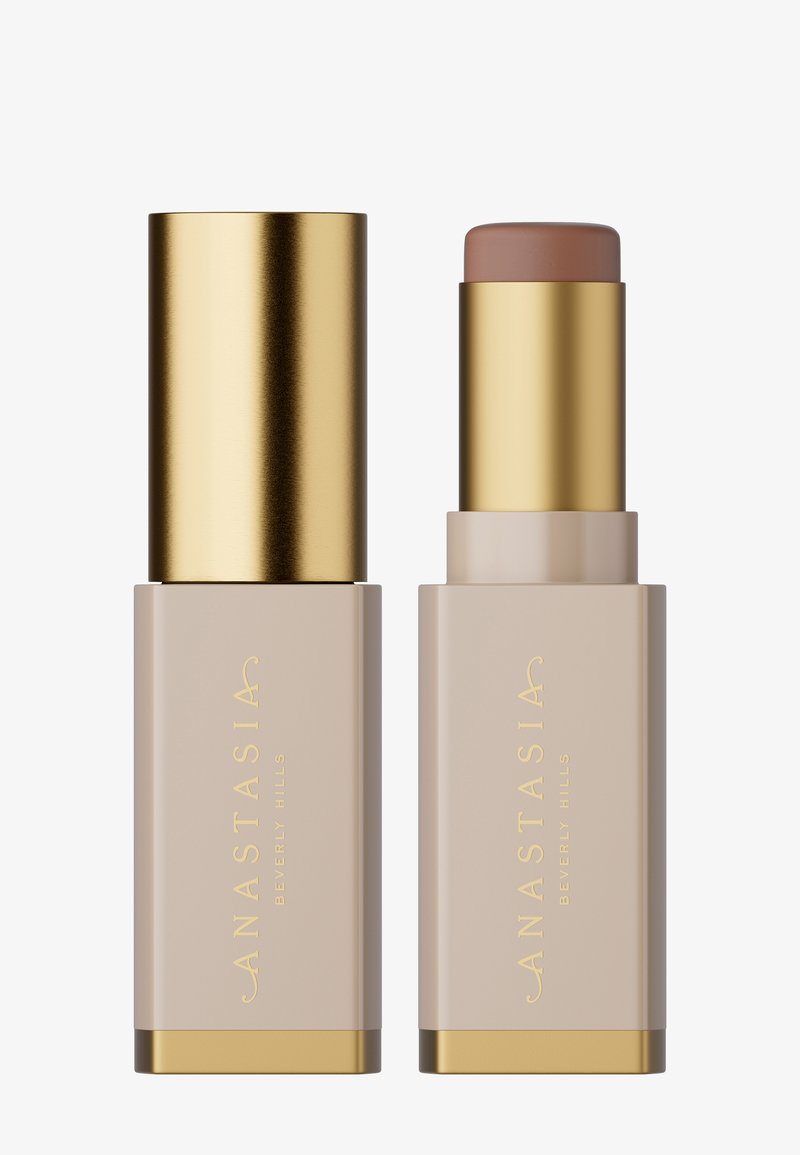 Stiftenfoundation met een beige container en gouden accenten. Heeft een gladde, ronde top met een lichtbruine inhoud.