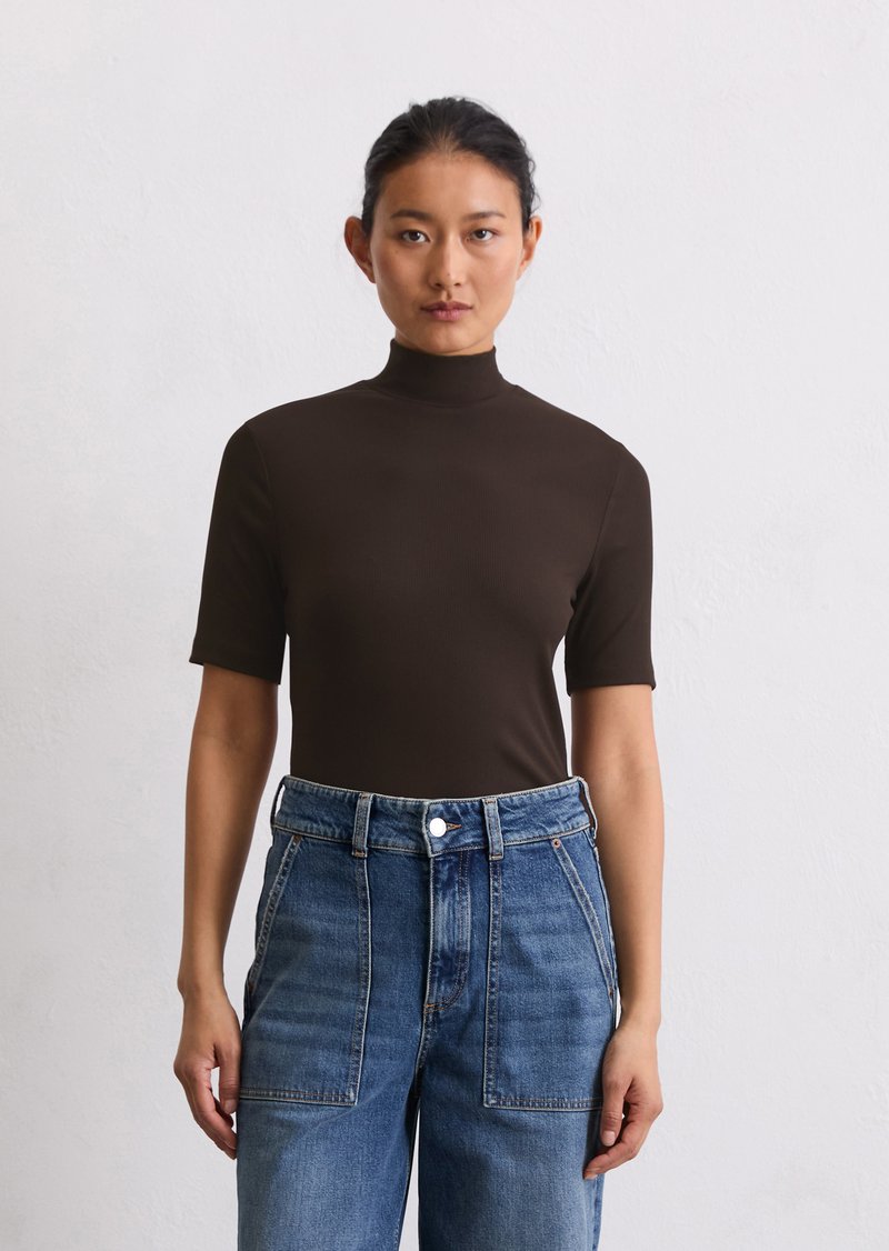 Haut marron à côtes, à manches courtes et col haut, associé à un jean en denim bleu clair taille haute avec de grandes poches avant.