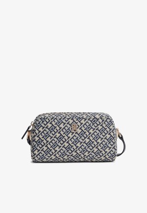 Trousse de toilette rectangulaire avec motif géométrique bleu, fond beige, emblème logo doré, fermeture éclair et anse latérale.