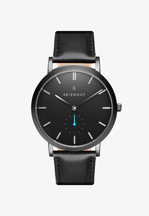 Sort ur med et rundt hus i rustfrit stål, minimalistisk sort urskive, sølv time-markører og en lille turkis sub-urskive. Sort læderrem.