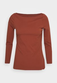 Top marrone a maniche lunghe con scollatura arrotondata, texture liscia, design aderente e spacchi laterali per una maggiore libertà di movimento.