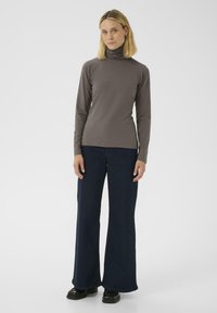 Dunkelgrauer Langarm-Turtleneck aus einem glatten Stoff, kombiniert mit weit geschnittenen, marineblauen Hosen und schwarzen Schuhen. Schlichtes Design, glatte Textur und ohne Muster.