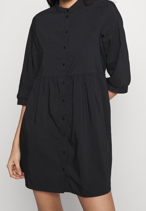 Schwarzes Hemdblusenkleid mit Dreiviertelärmeln, geraffter Taille und glatter Textur. Verfügt über verdeckte Druckknöpfe und Seitentaschen.