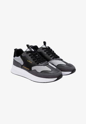 Chaussures de sport noires et grises avec des panneaux en mesh, semelle blanche épaisse, bout rond, lacets noirs et détail de logo doré sur le côté.