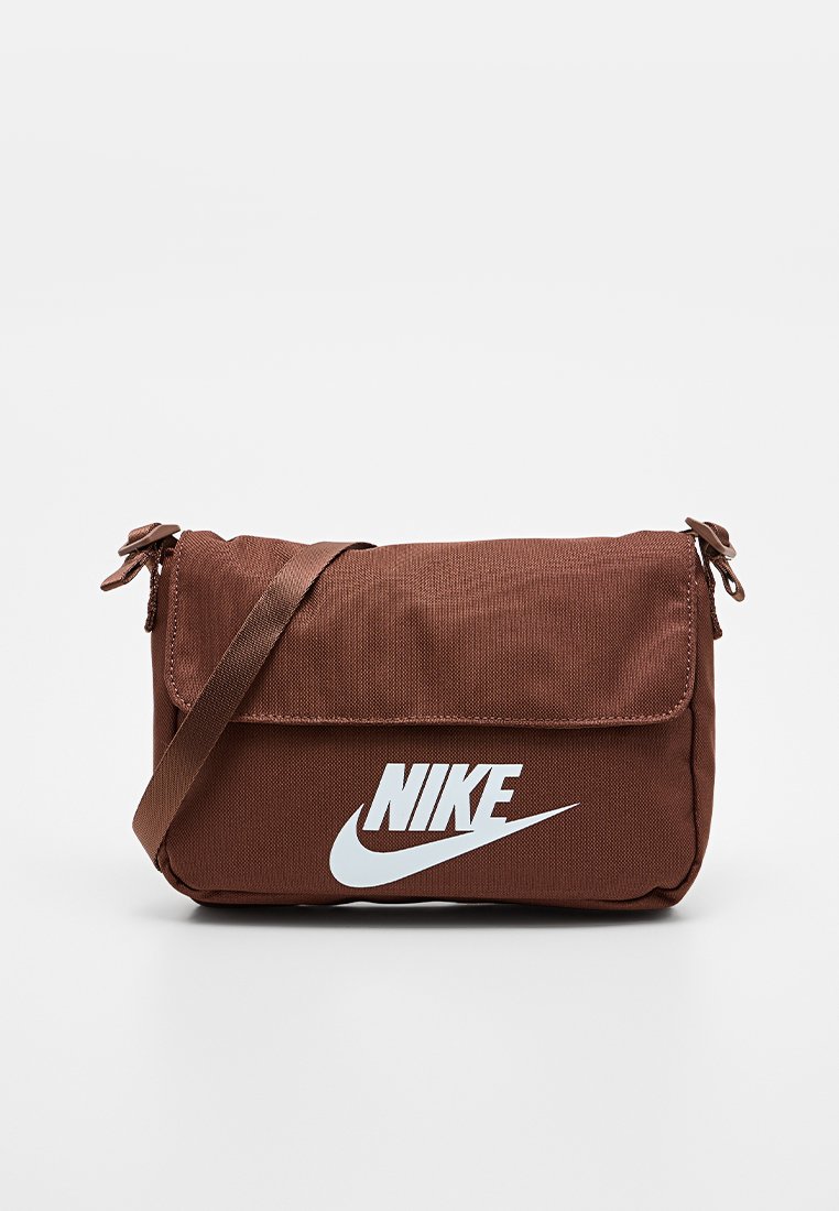 Bolso bandolera de tela marrón con cierre de solapa, con un gran logo blanco de Nike en la parte frontal. Incluye una correa marrón ajustable.
