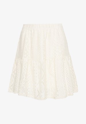 Jupe en dentelle de coton blanc avec taille élastique et ourlet évasé à volants, présentant des motifs géométriques et floraux.