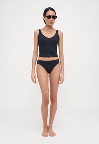 Black ribbed crop tank top and matching black bikini bottoms. The top features a scoop neckline, while the bottoms have a low-rise design.