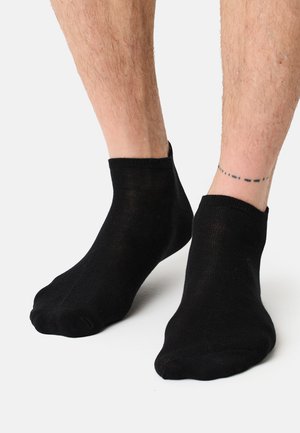 Calcetines tobilleros negros hechos de una tela delgada y elástica. El diseño presenta un corte bajo en el tobillo con una textura suave y talón reforzado.