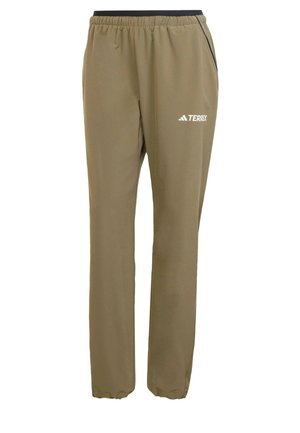 Khaki-kleurige trainingsbroek met een elastische tailleband, zwarte accenten en het Terrex-logo in het wit gedrukt op de linker dij. Gladde textuur.