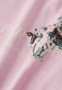 Różowy materiał z bukietem kwiatów i częściowo widocznym białym tekstem, w tym słowem "PARYŻ" w dużych literach.