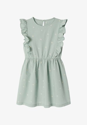 Light green sleeveless dress with ruffled shoulders and small white floral embroidery, gathered waist, and keyhole back closure.