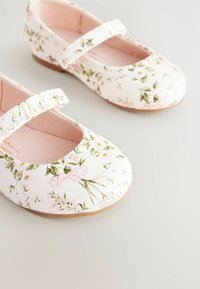 Scarpe Mary Jane stampate a fiori in finta pelle bianca, con una morbida fodera rosa, punta rotonda e una singola cinghia regolabile.