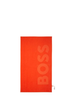 Serviette rectangulaire orange vif avec le mot "BOSS" embossé verticalement en grandes lettres sur le côté droit.
