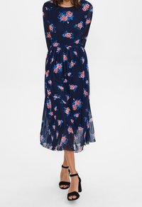 Vestido floral azul marino con mangas largas, que presenta un corsé ajustado y una falda fluida. Flores rosas y azules están distribuidas por toda la tela.