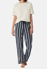 Beige Baumwoll-T-Shirt kombiniert mit marineblauen und cremefarbenen gestreiften Sweatpants, die einen elastischen Bund und einen Kordelzug haben und eine lockere Passform bieten.