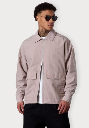 Light pink, zip-up jacket with a collar, two front pockets, and elastic cuffs. Made from a smooth fabric, featuring a relaxed fit and minimalist design.