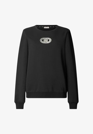 Bluză neagră cu mâneci lungi, cu manșete și tiv rib, având o decorare ovală argintie cu inițialele „CD” centrate pe piept.