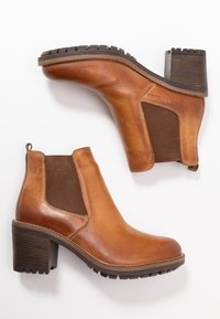 Braune Leder-Stiefeletten mit elastischen Seitenpaneelen, einem blockförmigen Absatz und einer gerippten Sohle. Glatte Textur mit kontrastierenden braunen Akzenten.