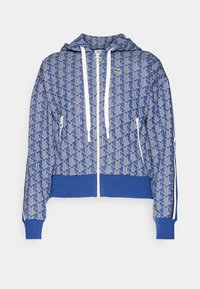 Sweat à capuche bleu zippé avec motif géométrique blanc, cordons blancs, poches avant zippées, poignets et bord-côte côtelés.