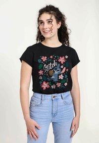 Černé bavlněné tričko s barevným potiskem Stitcha obklopeného růžovými květy a zelenými listy. Krátké rukávy a volný střih.