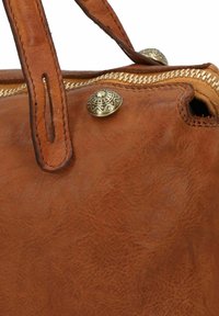 Bolso de cuero marrón con dobles asas, que presenta un detalle de broche de latón y un zipper en contraste. Superficie texturizada con grano visible.