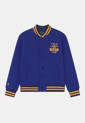 Blaue Collegejacke mit gelben Streifen am Kragen, an den Bündchen und am Saum, Fronttaschen, Knopfverschluss und "Polo Track 067 Team" Logo auf der Brust.