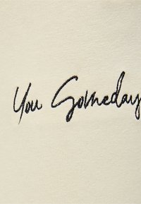 Tkanina v krémové barvě s černým kurzívním vyšitím, které říká "Jednou ty." Textura je hladká a mírně elastická.