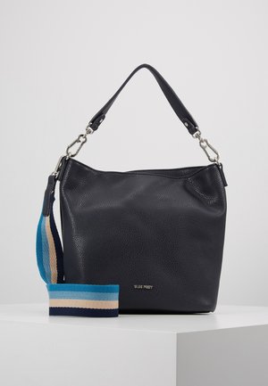 Sac à main en cuir noir avec poignée amovible et bandoulière en tissu rayé bleu, beige et marine sur surface blanche.