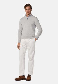 Grauer Baumwollpullover mit Reißverschlusskragen, kombiniert mit weißen Hosen und braunen Wildlederschuhen. Einfaches Design mit gerippten Bündchen und Saum.