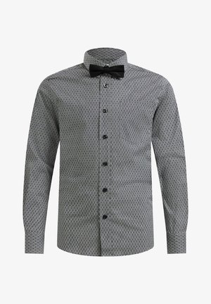 Camisa de manga larga con patrón en blanco y negro, cuello abotonado y pajarita negra. Cuenta con un bolsillo en el pecho y botones negros.
