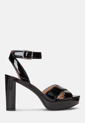 Czarne lakierowane sandały na grubym obcasie z platformą, z krzyżującymi się paskami i regulowanym zapięciem na kostkę.