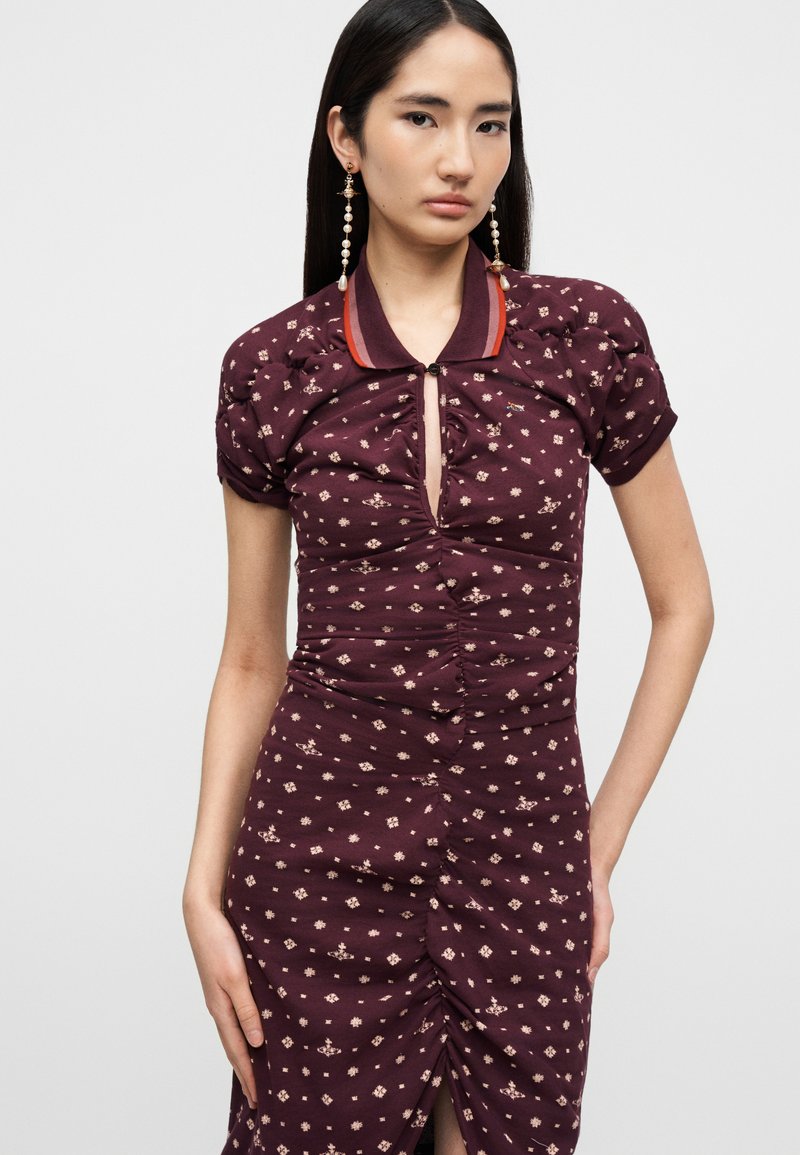 Kurzärmeliges, kastanienbraunes Kleid mit gerafftem Design, kontrastierendem Kragen, floralem Muster und einem Vorderschlitz. Akzente bilden dezente Knöpfe.