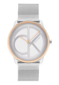 Sidabrinis tinklinis dirželis laikrodis su apvaliu sidabriniu ciferblatu, kuriame yra tekstūruota balta fono spalva ir ryškus auksu akcentuotas logotipo dizainas.