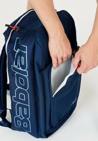 Marineblauwe rugzak met een gestructureerde stof, een groot hoofdvak en een zijvak. De rits heeft een contrasterende oranje trekker.