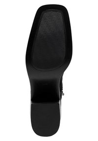 Semelle de chaussure noire avec une finition lisse, présentant des rainures horizontales pour l'adhérence. Le talon est de forme bloc et élégant.