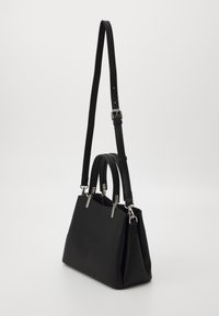 Sac à main en cuir noir avec double anses supérieures et une bandoulière réglable. Présente des accents métalliques et une forme rectangulaire structurée.