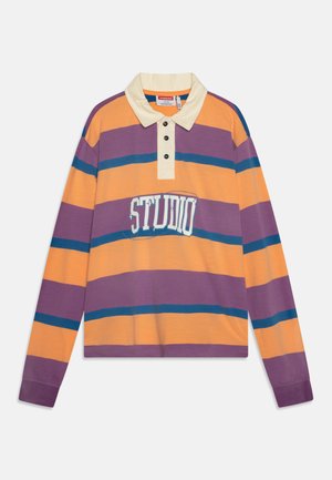 Polo cu mânecă lungă, în dungi portocalii, violet și albastre. Prezintă un guler crem, trei nasturi negri și un grafic "STUDIO" pe partea din față.