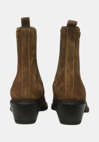 Stivaletti alla caviglia in suede marrone con una texture sottile, dotati di un tacco corto a blocco e dettaglio con cerniera all'interno. Logo stampato sul tacco.