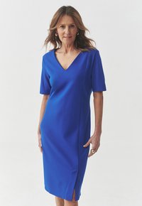 Blaues Kleid mit V-Ausschnitt, kurzen Ärmeln, geradem Schnitt und Seitenschlitzen. Die glatte Textur und das schlichte Design unterstreichen sein elegantes Aussehen.