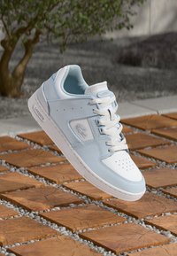 Lacoste sportiniai batai šviesiai mėlynos ir baltos odos. Yra perforuota nosis, plokščios raištelės ir logotipas šone. Lengvas dizainas su guminiu padu.
