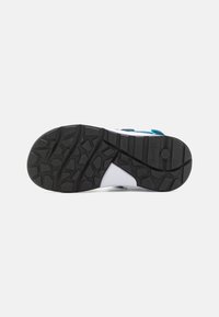 Sneaker mit einem mehrfarbigen Obermaterial in Weiß, Blau und Marine, einer schwarzen strukturierten Gummisohle mit einem robusten Profil.