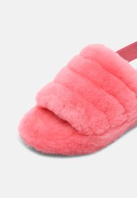 Chausson ouvert rose en peluche avec des brides épaisses et douces et une semelle rembourrée, conçu pour le confort à l'intérieur.