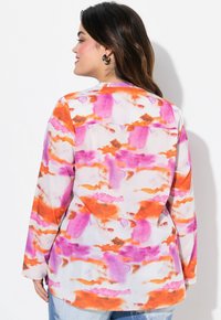 Camisa de manga larga con un patrón abstracto de acuarela en rosa, naranja y blanco. Tejido suave, escote redondo y corte relajado.
