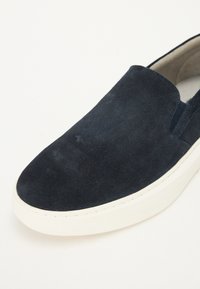 Scarpa slip-on in suede blu navale con suola in gomma bianca. Presenta pannelli elastici sui lati e una superficie liscia, progettata per un uso casual.