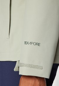 Light green TEXAPORE jacket with a smooth texture. Features a neat cuff with a Velcro strap and clean lines for a sleek design.