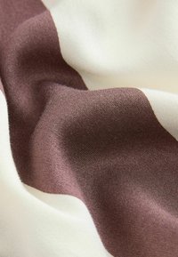 Textilstoff mit glatter Textur, der dunkelbraune und cremefarbene Streifen zeigt, wobei eine Farbmatte in einer drapierten Anordnung präsentiert wird.